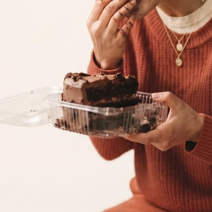 Pessoa segurando um pedaço de bolo de chocolate